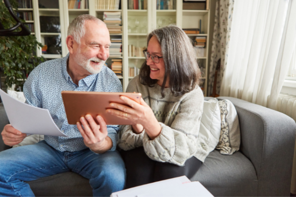 An older couple smiling holding an ipad